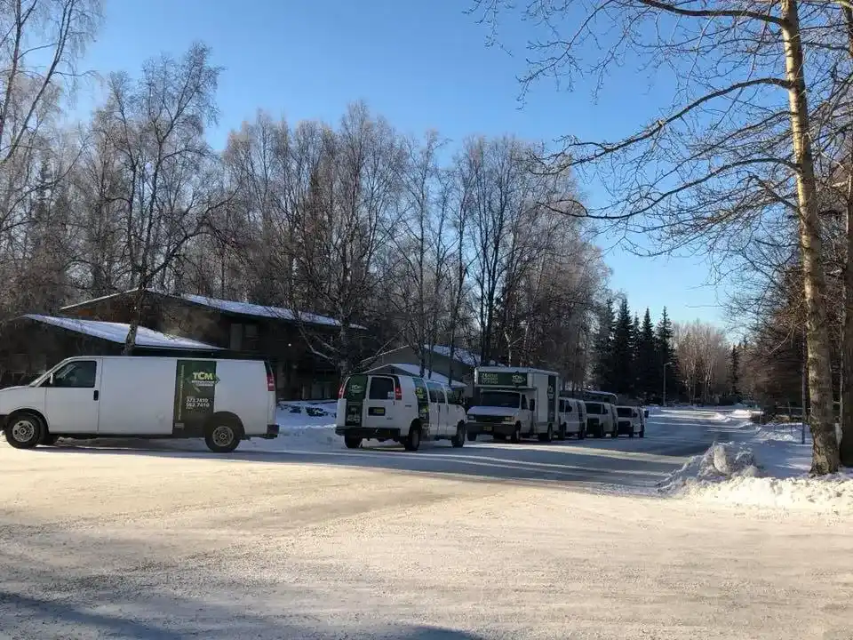 TCM Restoration vans and box trucks lined up on a snowy Anchorage street in winter